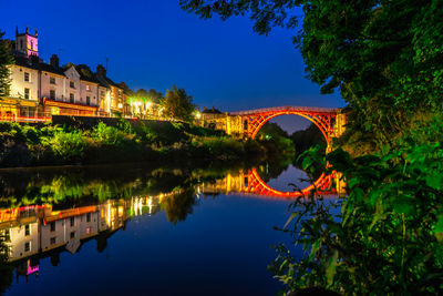 Arch bridge over river amidst buildings against sky