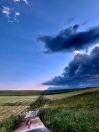 Road amidst field against sky