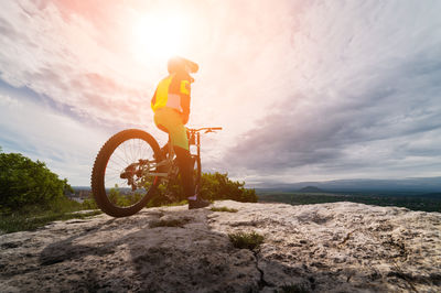 Guy sits on a mountain bike in a mountainous area against the backdrop of a private sector person