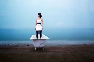 Woman standing in bathtub at beach