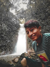 Portrait of young man sitting on rock