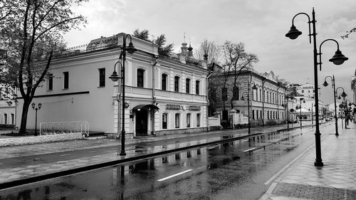 Street by buildings in city against sky