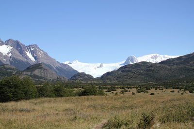 Scenic view of mountains and landscape against clear sky on sunny day during winter