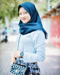 Portrait of smiling young woman standing on street in city