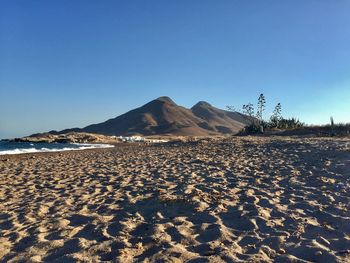 Scenic view of desert against clear blue sky