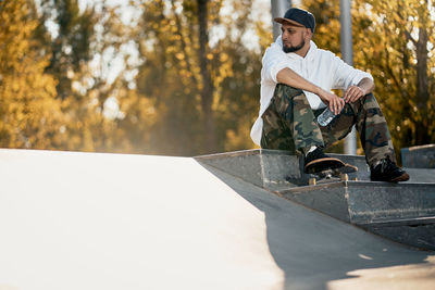 Man with skateboard sitting over steps in park