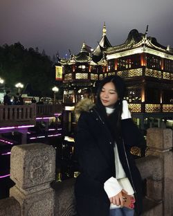 Woman standing against illuminated city at night