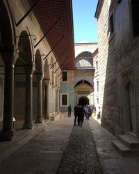 Rear view of people walking on street amidst buildings in city