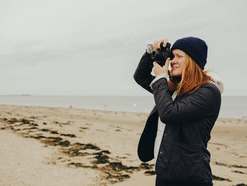 Woman taking photos on beach in scotland