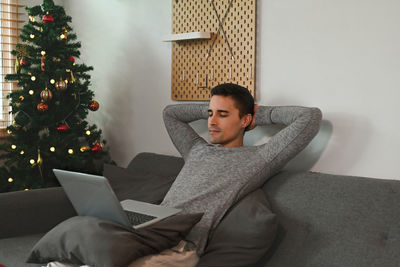 Man using laptop while relaxing on sofa at home