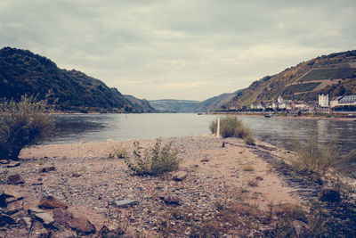 Scenic view of river by mountains against sky