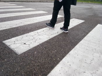 Low section of man walking on zebra crossing