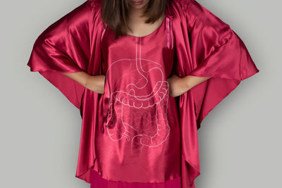 Midsection of woman standing against red background