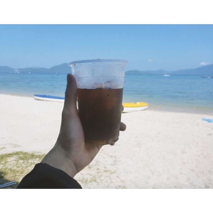 drink, beach, sea, refreshment, human hand, water, drinking glass, human body part, real people, holding, food and drink, horizon over water, shore, day, alcohol, sand, one person, personal perspective, outdoors, sky, vacations, summer, nature, close-up, leisure activity, sunlight, beer glass, drinking straw, beer, beauty in nature, clear sky, focus on foreground, lifestyles, men, scenics, freshness, people