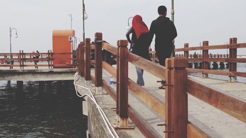 Rear view of man standing on pier against sky