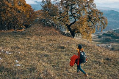 Rear view of woman walking on road during autumn