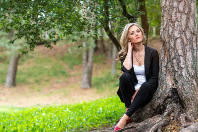 Portrait of woman sitting on tree trunk