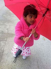 Portrait of cute girl playing with pink umbrella