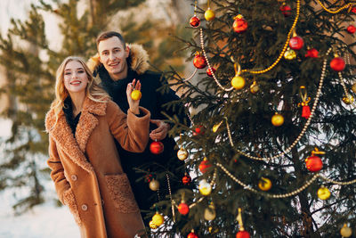 Portrait of smiling young woman holding christmas tree