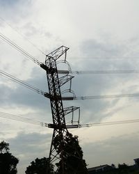 Low angle view of electricity pylon against cloudy sky