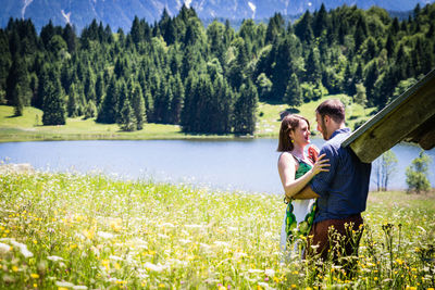 Side view of couple romancing while standing on grassy land