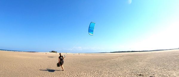 Person paragliding on beach against sky