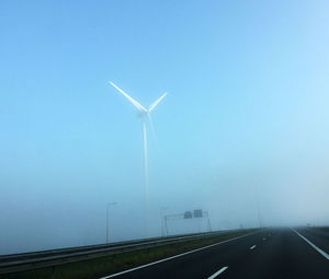 Wind turbines on landscape against clear blue sky