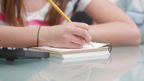 Midsection of girl writing in book