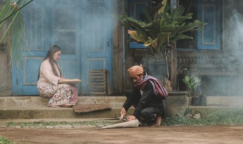 Full length of friends sitting on wall