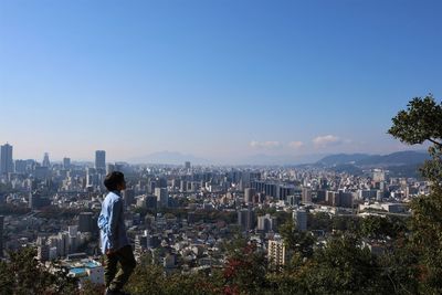 Boy looking at cityscape against sky