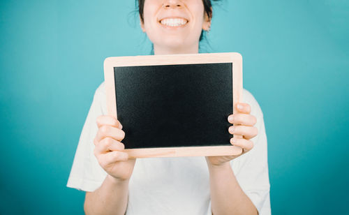 Midsection of woman holding digital tablet against blue background