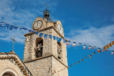 Church steeple with clock and flags at sunset at greoux-les-bains, in the french provence.