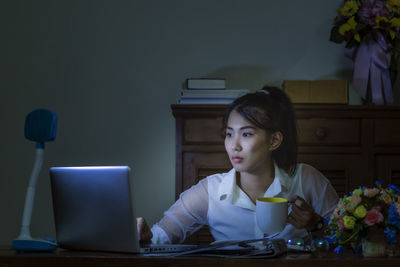 Woman looking at camera while sitting on table