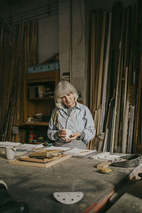 Senior craftswoman holding cup while standing at workshop