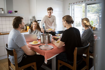 Man serving food for family at dining table