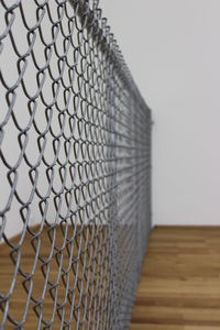 Close-up of fence on table against wall