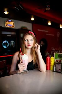 Portrait of a young woman drinking glass at restaurant