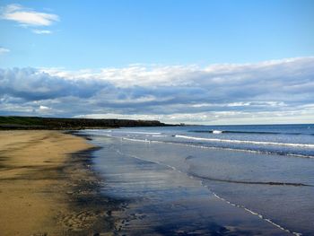 Scenic view of beach against cloudy sky