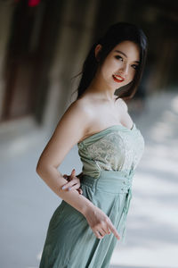 Portrait of young woman standing against wall