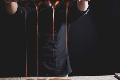 Midsection of man pouring melted chocolate