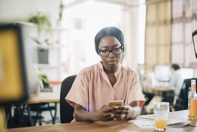 Creative young businesswoman using mobile phone at desk in office