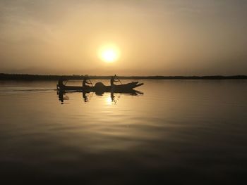 Silhouette man in lake against sky during sunset