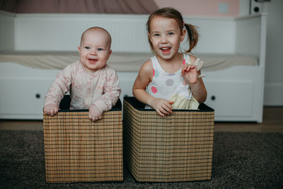 Brother and sister are playing at home, climbed into the toy baskets. smile and look into the frame
