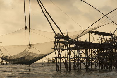 Fishing nets over sea against sky during sunset