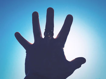 Low angle view of person hand against sky