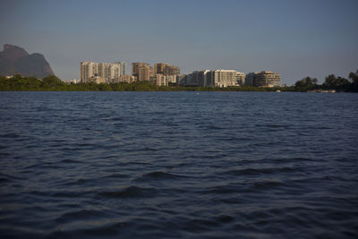 Sea by buildings against clear sky