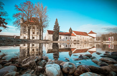 Reflection of bare trees and buildings in lake