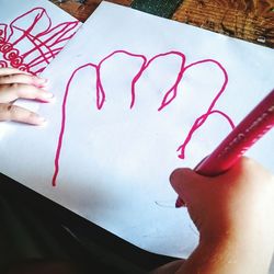 Cropped image of hand holding heart shape on wall