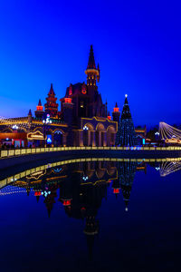 Illuminated bridge over river in city at night