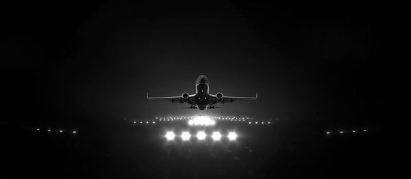 Low angle view of airplane flying in sky at night